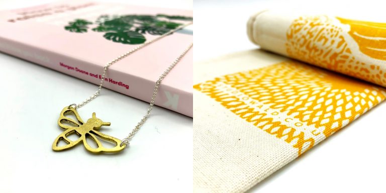 An item of bee-shaped jewlery and a decorative tea towel, gifts available at the Manchester Museum Shop