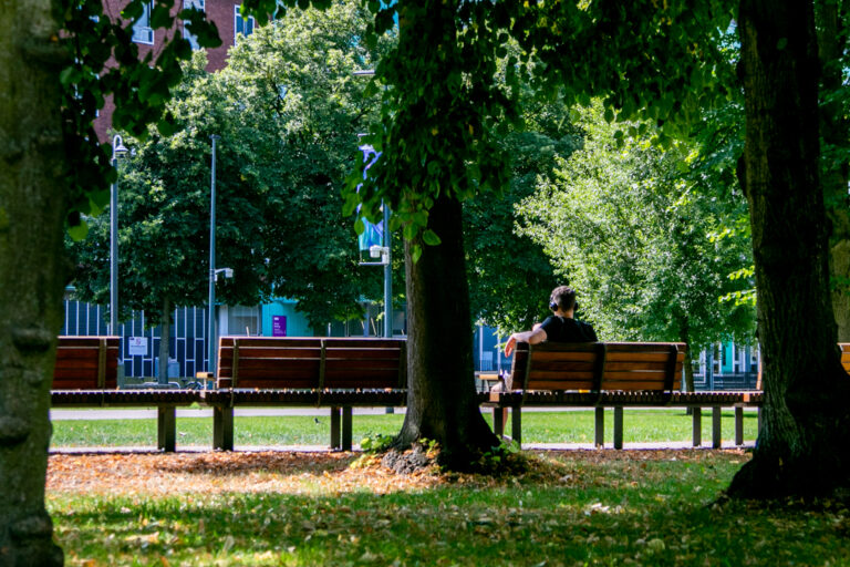 A person with headphones on enjoying the sun in Bruswick Park