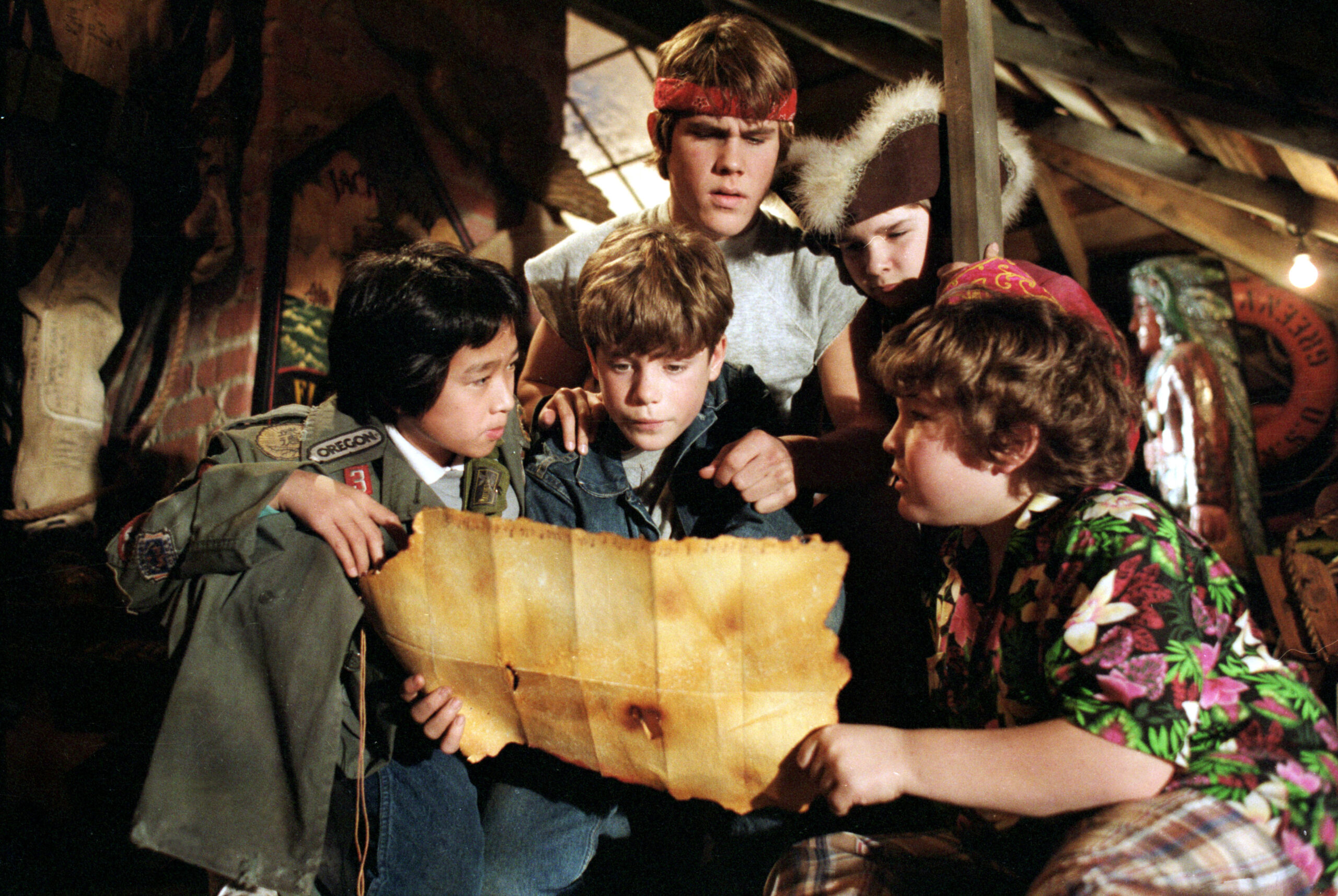 A screenshot of the cast of The Goonies looking at a map to One Eyed Willie's treasure