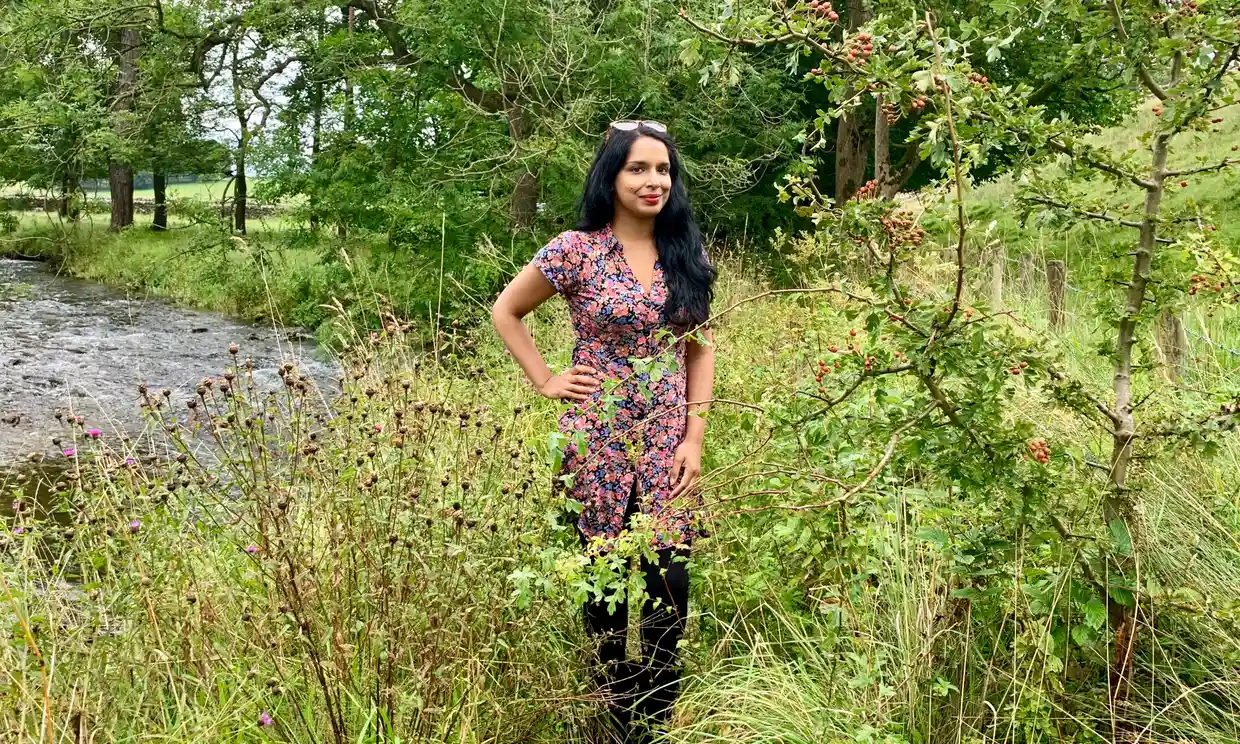 Award-winning author, Anita Sethi posing in a green, leafy space