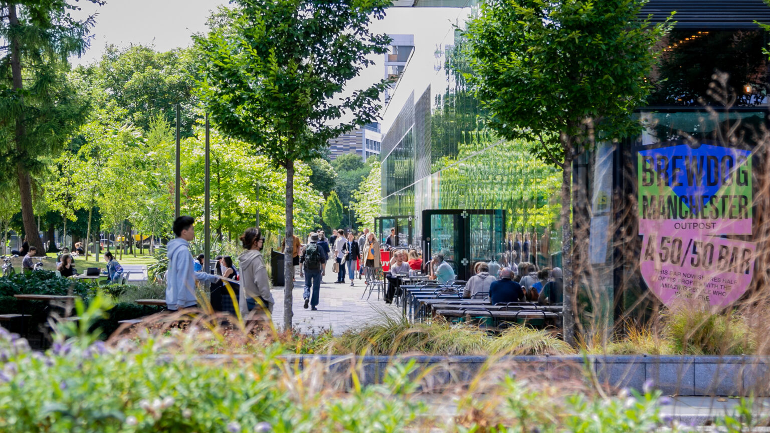 People enjoying sunshine outside Brewdog on University Green one of the many green spaces on Oxford Road in Manchester